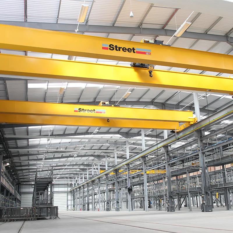 Dua overhead crane StreetCrane berwarna kuning di dalam gudang industri
